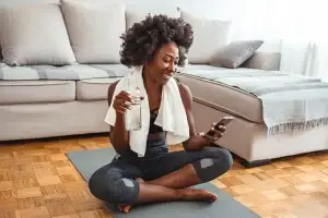 Femme noire aux cheveux afro qui fait du yoga dans son salon - santé mentale