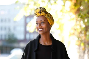 Femme noire souriante coiffée d'un turban jaune - Affirmations positives estime de soi