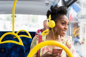 Femme noire qui écoute de la musique avec son casque dans le bus - Ces musiques qui font du bien au moral
