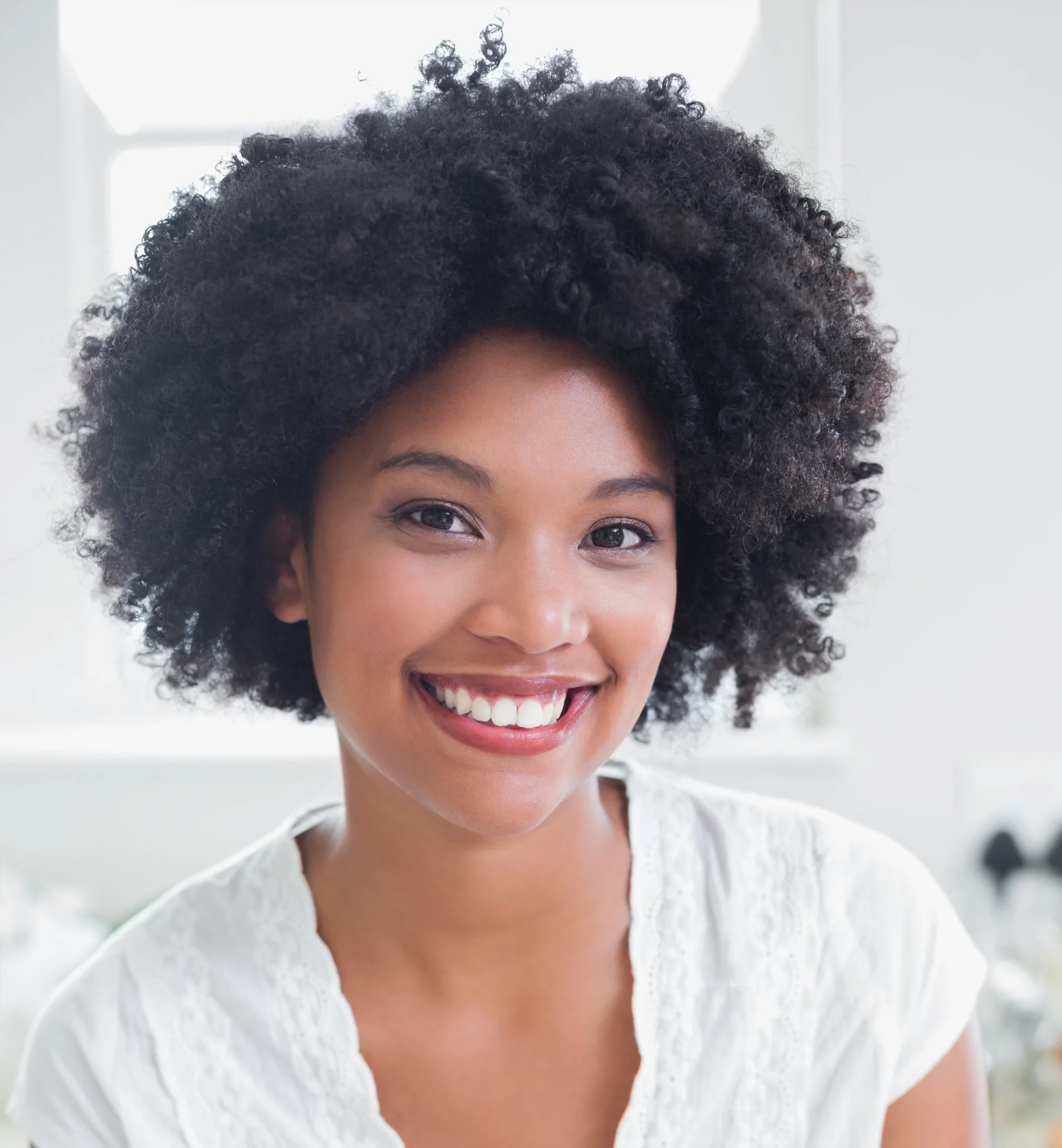 Femme noire souriante coiffée d'un afro aux cheveux naturels